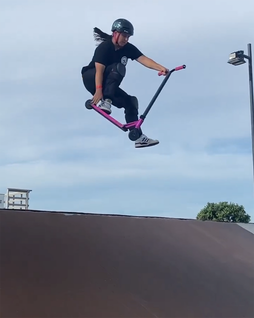 Pro scooter rider Emily Gibson doing a jump on a ramp