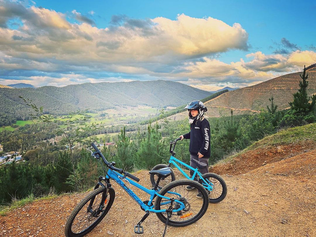 Trey Wiley bmx rider in Victoria wearing a Wild Riders hoodie and standing by bikes on a mountain